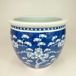 Peut inclure: Un pot en céramique bleu et blanc avec un motif floral. Le pot est rond et a un bord large.