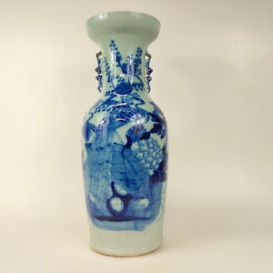 Op de afbeelding: Een blauwe en witte porseleinen vaas met een paar pauwen en bloemmotieven. De vaas heeft twee handvatten en een smalle hals.