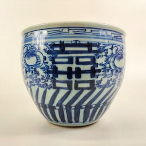 Peut inclure: Un bol en porcelaine bleu et blanc avec un motif chinois traditionnel. Le bol présente un motif répétitif de fleurs stylisées et le caractère chinois pour "double bonheur" au centre.