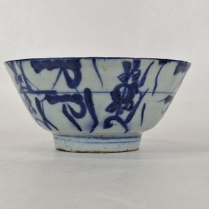 Peut inclure: Bol en céramique blanc et bleu avec un bord évasé et une base à pied. Le bol est décoré de motifs floraux et abstraits bleus. Le bol est probablement utilisé pour servir des aliments ou comme pièce décorative.