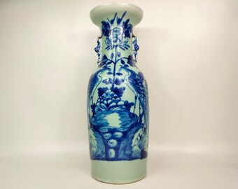 以下が含まれることがあります： 青と白の磁器製の壺で、鶴と花の模様が描かれています。壺には両側に取っ手が2つあり、薄い緑色の釉薬がかかっています。