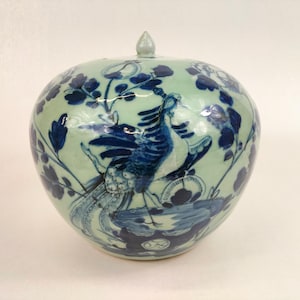 Peut inclure: Un pot en porcelaine bleu et blanc avec un couvercle, décoré d'un phénix et de motifs floraux. Le pot est recouvert d'un glacis vert clair.