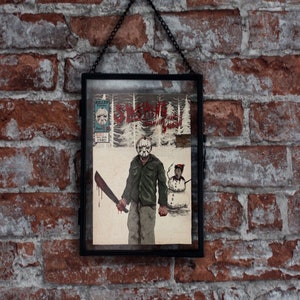 Könnte beinhalten: Eine gerahmte Illustration eines Comic-Covers mit einer Figur mit einer Hockeymaske, die eine Machete hält. Das Comic-Cover trägt den Titel "Slasher in the Snow" und die Figur trägt ein grünes Hemd und Jeans. Der Hintergrund ist eine schneebedeckte Waldszene.