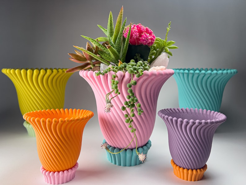 May include: Five colorful ceramic planters with a unique swirl design. The planters are in shades of yellow, orange, pink, teal, and purple. The pink planter has a succulent plant inside.