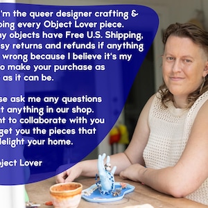 May include: A person sitting at a table with a blue ceramic hand ring holder. The ring holder is filled with rings and a blue beaded necklace. The person is wearing a white crocheted top. The text "Hi - I'm the queer designer crafting & shipping every Object Lover piece. All my objects have Free U.S. Shipping, & easy returns and refunds if anything goes wrong because I believe it's my job to make your purchase as easy as it can be. Please ask me any questions about anything in our shop. I want to collaborate with you and get you the pieces that will delight your home. ~ Object Lover" is visible in the image.