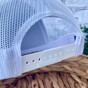 Close-up view of the adjustable snapback closure on a Richardson 112 trucker hat with breathable white mesh back panels.