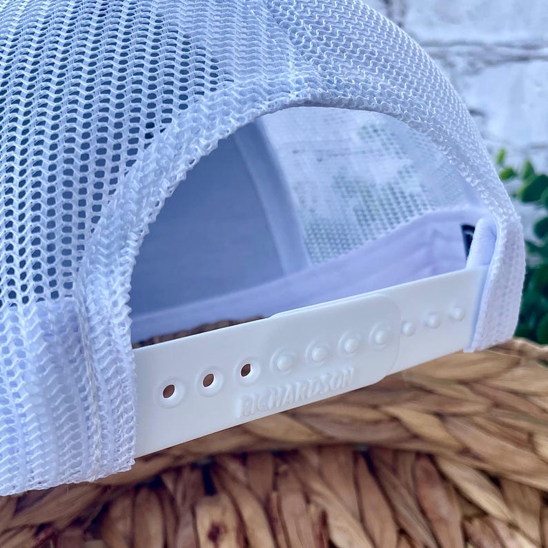 Close-up view of the adjustable snapback closure on a Richardson 112 trucker hat with breathable white mesh back panels.