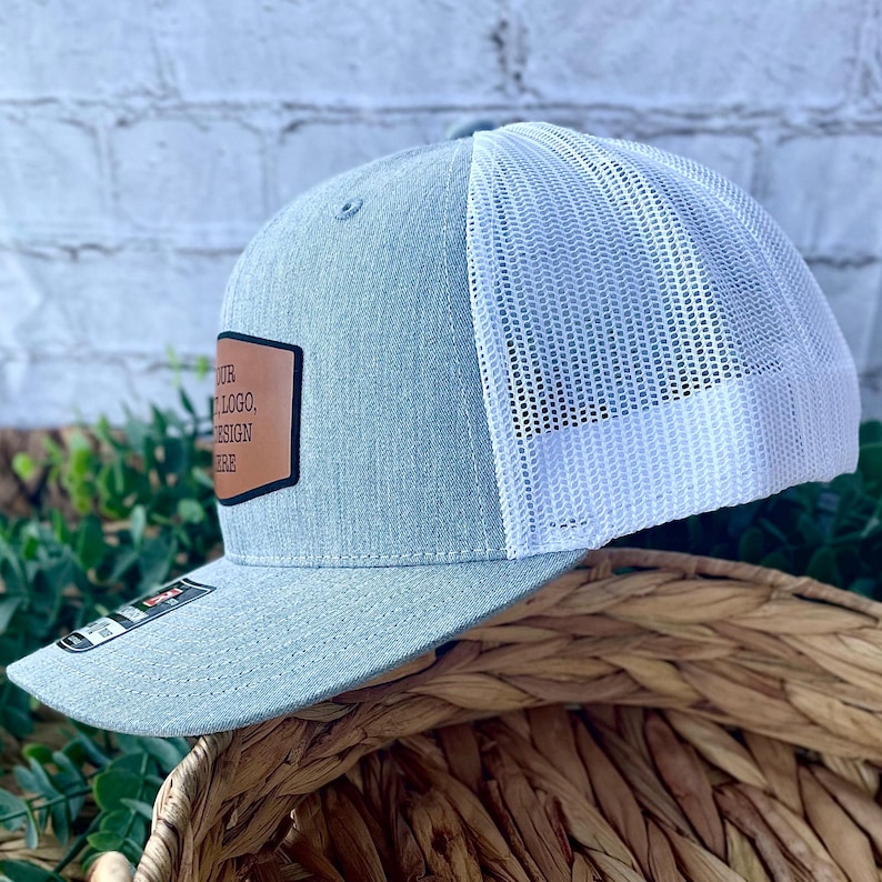 Side profile of a custom Richardson 112 trucker hat in heather grey with white mesh and engraved leather patch on the front.