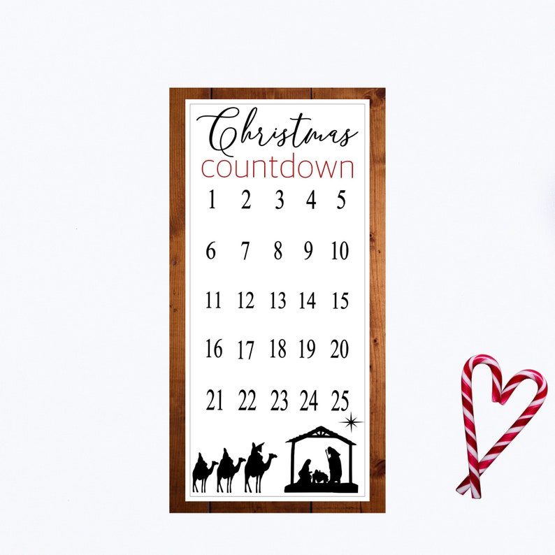 May include: A wooden sign with a Christmas countdown from 1 to 25. The sign has a brown woodgrain background and white text. The sign also features a silhouette of a nativity scene with three camels and a star.
