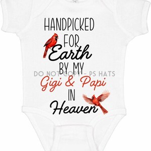 May include: White baby onesie with the text "HANDPICKED FOR Earth BY MY Gigi & Papi IN Heaven" and two red cardinal birds.