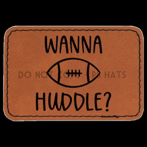 May include: Brown leather patch with black stitching and the text "Wanna Huddle?" with a football graphic.
