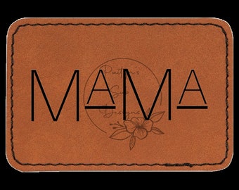 Könnte beinhalten: Ein braunes Leder-Patch mit dem Wort "MAMA" in schwarzen Buchstaben. Das Patch hat einen genähten Rand und ein kleines Blumenmuster.