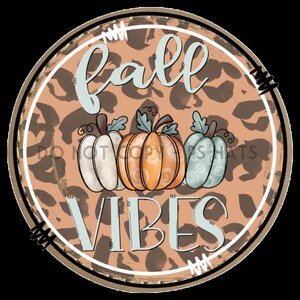 以下が含まれることがあります： 茶色のヒョウ柄の背景を持つ丸い看板。"fall vibes"という文字が青で書かれており、中央には3つのカボチャがあります。カボチャは白、オレンジ、青です。
