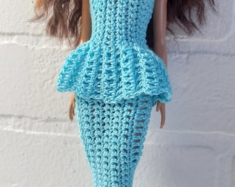 May include: A blue crocheted mermaid-style dress with a one-shoulder design. The dress has a ruffled bodice and a flowing skirt.