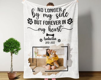 May include: White memorial blanket with black text that reads "No longer by my side but forever in my heart."  A bone icon is below the text.  The name "Isabella" and the dates "2012-2022" are below the bone icon.  A photo of a woman holding a dog is in a black frame on the blanket.