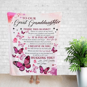 May include: Pink and white fleece blanket with a message to a great granddaughter. The message includes the words "Inside this blanket", "It is full of love", "I believe in you", "Hugging you!" and "Love, Great Grandma and Grampa". The blanket is decorated with pink butterflies.