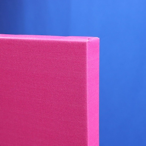 May include: Close-up of the edge of a pink canvas print with a white and black cartoon design. The canvas is wrapped around the edges of the frame.