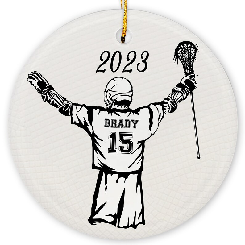 May include: A black and white illustration of a lacrosse player with their arms raised in the air. The player is wearing a jersey with the name "BRADY" and the number "15" on the back. The year "2023" is printed above the player.