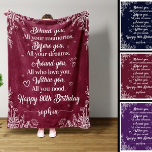 May include: A maroon fleece blanket with white floral designs and the text "Behind you, All your memories. Before you, All your dreams. Around you, All who love you. Within you, All you need. Happy 80th Birthday sophia" printed on it.