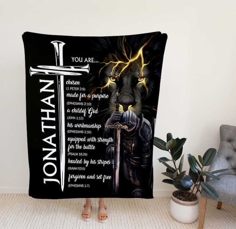 May include: Black and gold fleece blanket with a lion's face and a knight holding a sword. The blanket has the name "JONATHAN" and a religious message with bible verses.