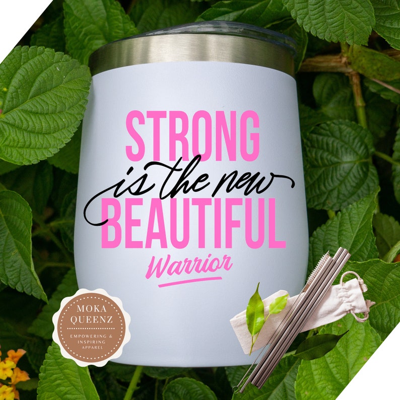 Puede incluir: Un vaso aislado blanco con tapa plateada, con el texto "STRONG is the new BEAUTIFUL Warrior" en rosa y negro. Incluye pajitas de acero inoxidable y una peque&ntilde;a bolsa de transporte. Rodeado de hojas verdes.