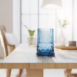 May include: A blue glass candle holder with a textured design sits on a wooden table.