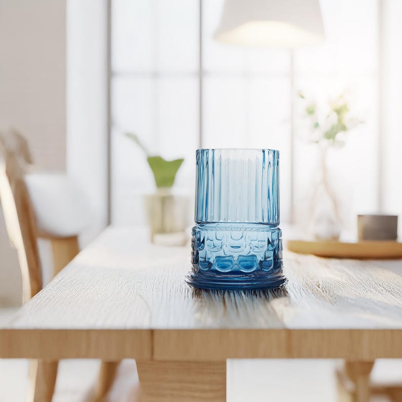May include: A blue glass candle holder with a textured design sits on a wooden table.