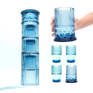 May include: Set of six blue glass tumblers with a fluted design. The tumblers are stacked in a tower, with one tumbler being held in a hand.