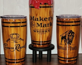 Może przedstawiać: Trzy kubki ze stali nierdzewnej z wzorem drewna. Kubki są ozdobione logo Crown Royal, Maker's Mark Kentucky Straight Bourbon Whisky i Buffalo Trace Kentucky Straight Bourbon Whiskey.
