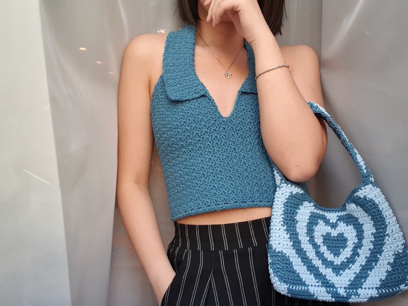 May include: A blue crocheted halter top with a collared neckline and a blue and white crocheted heart-shaped handbag.