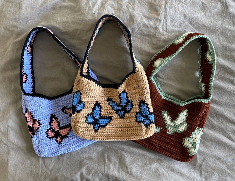 May include: Three crocheted handbags with butterfly designs. The bags are in blue, brown, and beige.