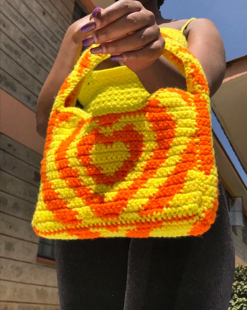 May include: A yellow and orange crocheted tote bag with a heart design.
