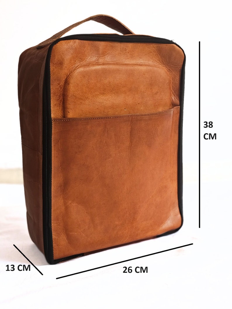 May include: A brown leather travel bag with a black zipper and black trim. The bag measures 13 cm wide, 26 cm long, and 38 cm tall.