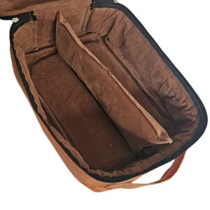May include: A brown leather travel bag with a zip closure and a handle. The bag is open and the interior is lined with brown fabric. The bag has two compartments.
