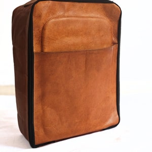 May include: A brown leather travel bag with a black zipper and a black handle.