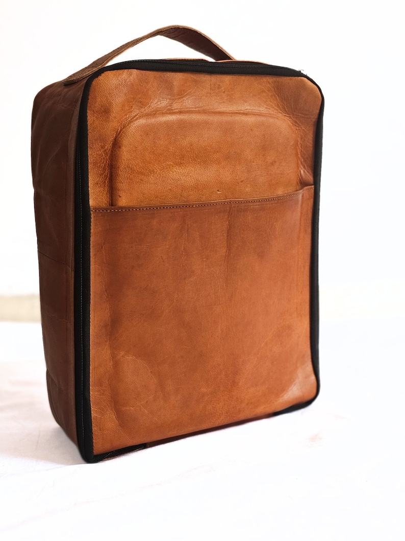 May include: A brown leather travel bag with a black zipper and a black handle.