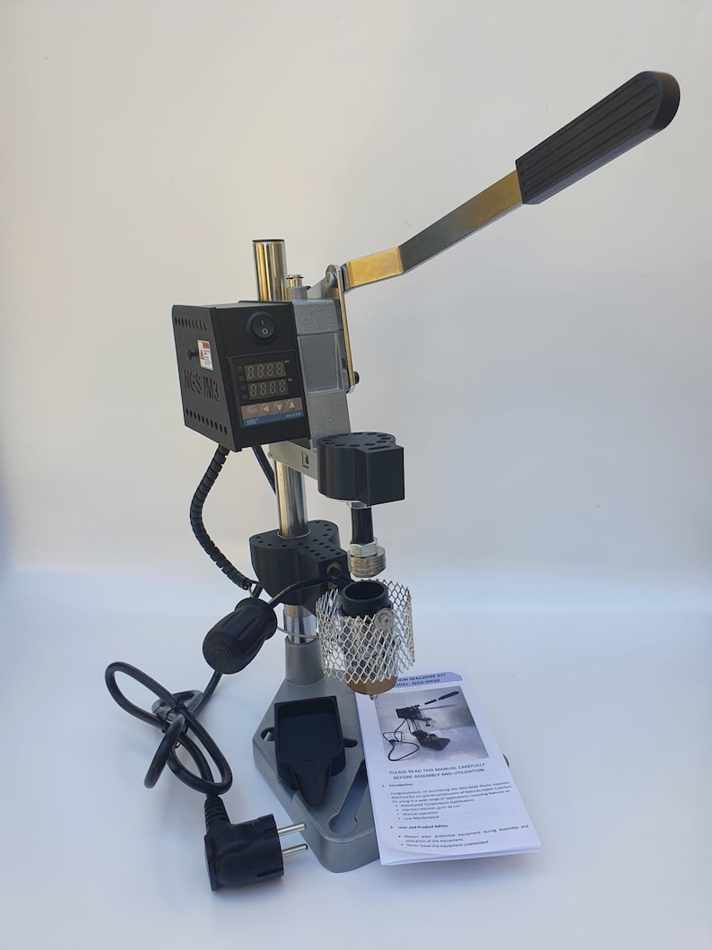 May include: A silver and black heat press machine with a digital display and a lever. The machine has a power cord and a foot pedal. The machine is on a white surface.  "PLEASE READ THIS MANUAL CAREFULLY BEFORE ASSEMBLING AND OPERATING THIS MACHINE."