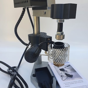 May include: A silver and black industrial machine with a digital display reading "0.000.0". The machine has a black power cord and a black handle. The machine is labeled "NGS IM3".