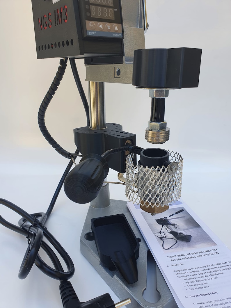 May include: A silver and black industrial machine with a digital display reading "0.000.0". The machine has a black power cord and a black handle. The machine is labeled "NGS IM3".