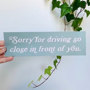 May include: A light blue sign with white text that reads "Sorry for driving so close in front of you."