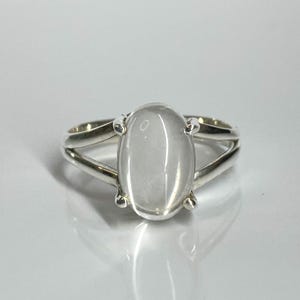 Op de afbeelding: Een zilveren ring met een heldere, ovale edelsteen. De ring heeft een delicaat, dubbelband ontwerp.