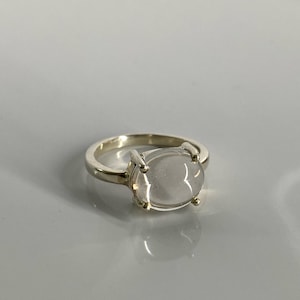 May include: A silver ring with a clear oval-shaped gemstone.
