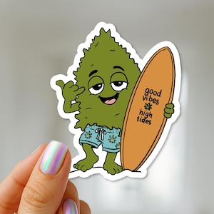 May include: A die-cut sticker featuring a cartoon green cannabis bud character with a relaxed expression, wearing light blue patterned swim trunks, making a shaka hand gesture, and holding a tan surfboard with the text good vibes high tides.