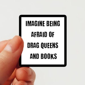 Op de afbeelding: Een witte vierkante sticker met zwarte tekst die "Imagine being afraid of drag queens and books" zegt.