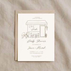 以下が含まれることがあります： カフェのイラストが描かれたベビーシャワーの招待状。招待状には「Cafe Bebe」と「Baby Shower」の文字と、JosieとMicahの名前が記載されています。招待状は、お揃いの封筒が付いたクリーム色のカードに印刷されています。