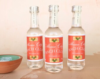 May include: Three small clear glass bottles with labels that say "Mexico City Bach Club" and "December 2022". The labels feature a cactus design and are in shades of orange, yellow, and green.