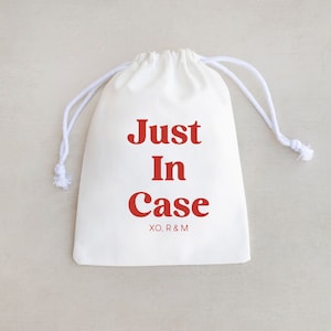 May include: White drawstring bag with the text "Just In Case" in red lettering. The bag has a white drawstring and is made of a soft, natural fabric.
