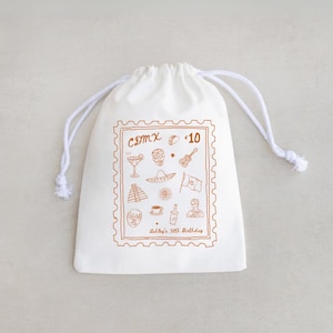 May include: White drawstring bag with a brown stamp-like design featuring Mexican cultural icons. The design includes a cocktail, skull, guitar, sombrero, flag, pyramid, coffee cup, bottle, and a person. Text reads "CDMX $10" and "Ashley's 30th Birthday."