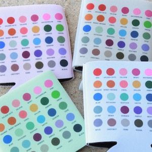 May include: Four white can coolers with a colour chart of 25 different colours. Each colour has a name written below it. The colours are arranged in rows of five. The colours include red, orange, yellow, green, blue, purple, brown, grey, and black.