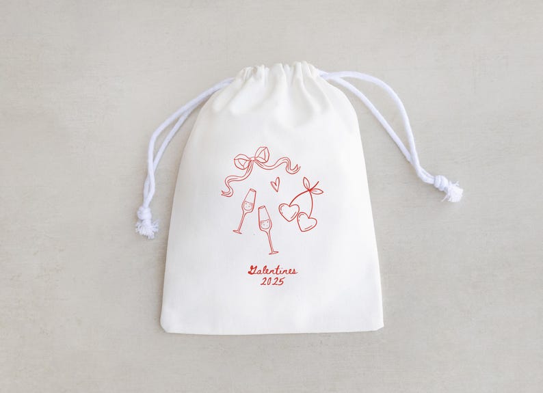 Pu&ograve; includere: Borsa di cotone bianco con coulisse, con un design rosso di due bicchieri di champagne, un fiocco e due cuori. Il testo "Valentines 2025" &egrave; stampato in rosso sotto il design.
